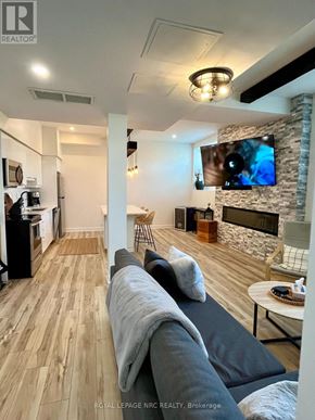 St. Catharines (Oakdale) condo for rent - A modern living room with a stone fireplace and a flat screen TV mounted above it.