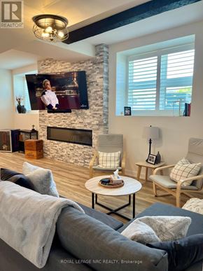 St. Catharines (Oakdale) condo for rent - A living room with a stone fireplace and a flat screen TV mounted above it.