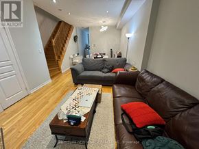 Toronto (Newtonbrook West) townhouse for rent - A living room with a brown leather couch and a coffee table with a red pillow on it.