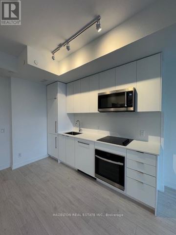 Toronto (Willowdale East) condo for rent - A modern kitchen with white cabinets and a microwave above the oven.