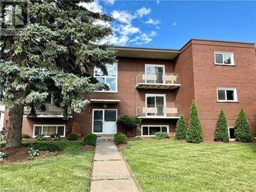 St. Catharines (Carlton/Bunting) condo for rent - A red brick apartment building with a tree in front.
