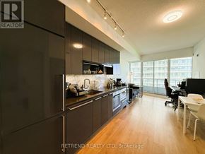 Toronto (Bayview Village) condo for rent - A modern kitchen with dark wood cabinets and a large window.