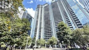 Toronto (Lansing-Westgate) condo for rent - A tall building with many windows is surrounded by trees.