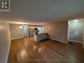 London North (North F) apartment for rent - A spacious room with wooden flooring and a kitchen area in the background.