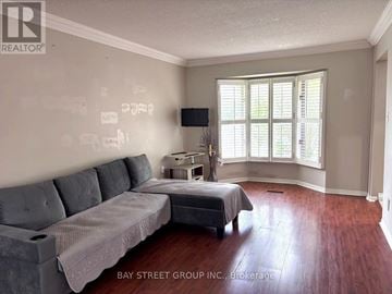 Markham (Thornlea) apartment for rent - A living room with a grey couch and a bed with a grey bedspread.