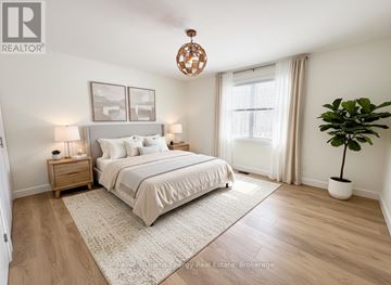 Prince Edward County (Wellington Ward) apartment for rent - A bedroom with a large bed, a nightstand with a lamp, a window with curtains, and a potted plant.
