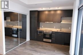 Toronto (Waterfront Communities) condo for rent - A modern kitchen with dark wood cabinets and stainless steel appliances.