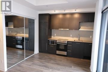 Toronto (Waterfront Communities) condo for rent - A modern kitchen with dark wood cabinets and stainless steel appliances.