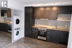Toronto (Waterfront Communities) condo for rent - A modern kitchen with dark wood cabinets and stainless steel appliances.