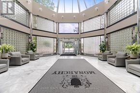 Mississauga (City Centre) condo for rent - A spacious lobby with a glass ceiling and a carpet that reads "Welcome to the home of the future".