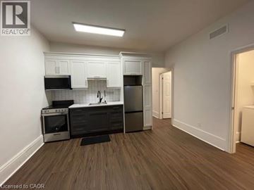 Kitchener apartment for rent - A kitchen with white cabinets and black appliances.
