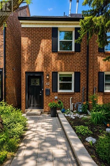 Toronto (Greenwood-Coxwell) townhouse for rent - A brick house with a black door and windows with shutters.