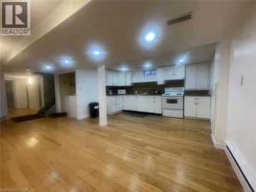 Welland apartment for rent - A spacious kitchen with white cabinets and a wooden floor.