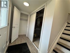 Welland townhouse for rent - A hallway with a staircase and a door leading to a utility room.
