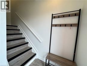 Welland townhouse for rent - A staircase with a wooden handrail and a bench at the bottom.