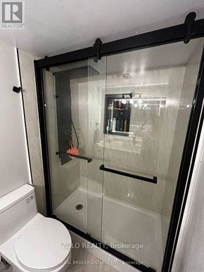 Hamilton (Ainslie Wood) condo for rent - A white toilet is in a glass shower stall.
