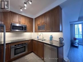 Toronto (Bay Street Corridor) condo for rent - A kitchen with wooden cabinets and a black counter top.