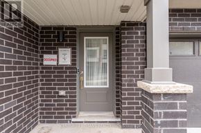 Oshawa (Eastdale) townhouse for rent - A grey door with a glass window and a sign that says "OCCUPIED" on a brick wall.