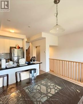 Oshawa (Windfields) townhouse for rent - A kitchen with a table and chairs in the foreground and a balcony with a railing in the background.