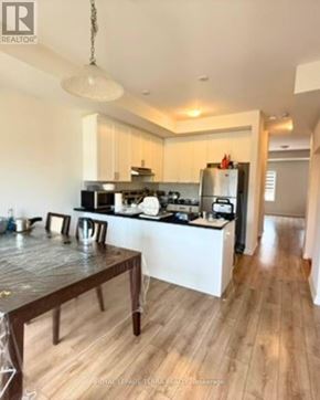 Oshawa (Windfields) townhouse for rent - A kitchen with a wooden table and a white fridge.