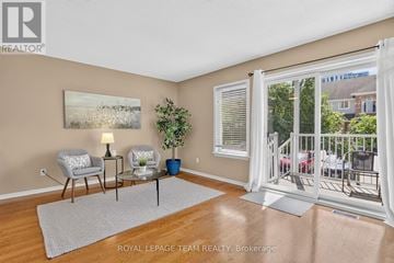 Ottawa townhouse for rent - A living room with a grey rug, a grey chair, a small table with a plant and a lamp on it, and a painting on the wall.