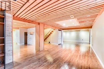 Pickering (Rosebank) apartment for rent - A spacious room with wooden floors and a staircase in the background.