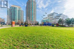 Toronto (Woburn) condo for rent - A park with a grassy area and a playground in the foreground, with apartment buildings in the background.