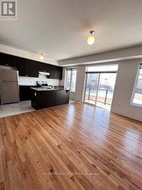 Whitby (Port Whitby) townhouse for rent - A real estate listing image of a kitchen and living room with wood flooring.