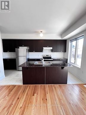 Whitby (Port Whitby) townhouse for rent - A kitchen with a wooden floor and a stainless steel refrigerator.