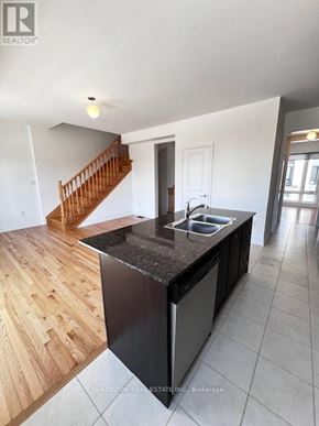 Whitby (Port Whitby) townhouse for rent - A modern kitchen with a wooden floor and black countertops.