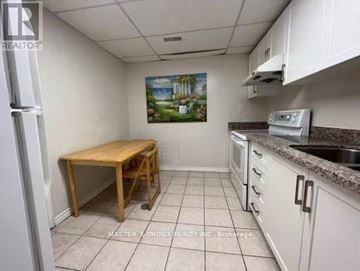 Toronto (Hillcrest Village) apartment for rent - A kitchen with white cabinets and a wooden table.