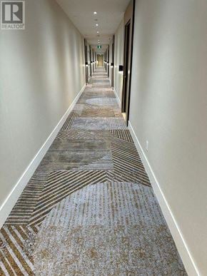 Toronto (Englemount-Lawrence) condo for rent - A long hallway with a carpeted floor and white walls.