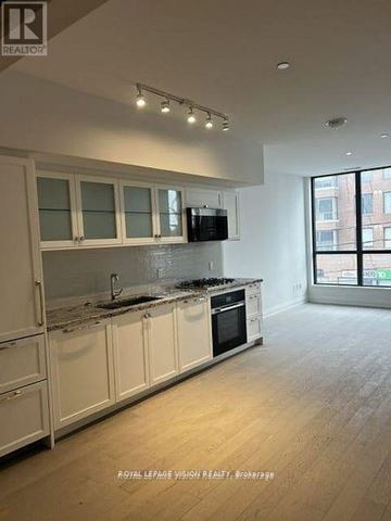 Toronto (Englemount-Lawrence) condo for rent - A modern kitchen with white cabinets and a wooden floor.