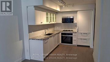 Toronto (Englemount-Lawrence) condo for rent - A kitchen with white cabinets and a granite countertop.
