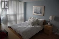 Toronto (Bay Street Corridor) condo for rent - A bed with a white comforter and pillows sits in a room with a picture on the wall.