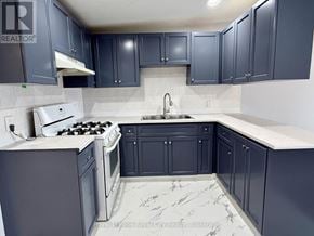 Guelph (Downtown) multi-family for rent - A kitchen with dark blue cabinets and a white stove top oven.