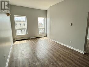 Guelph (Downtown) multi-family for rent - A room with wooden flooring and two windows.