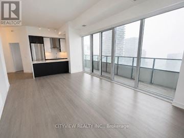 Toronto (Mimico) condo for rent - A spacious room with a bar area and large windows.