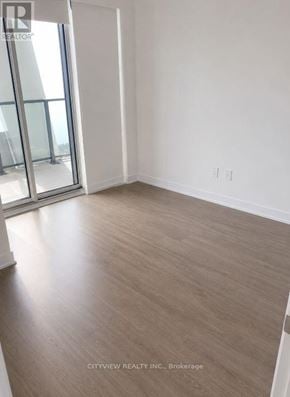 Toronto (Mimico) condo for rent - A room with a wooden floor and a sliding glass door.