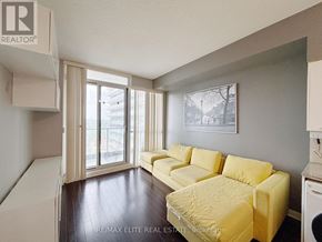 Toronto (Bayview Village) condo for rent - A living room with a yellow couch and a washing machine in the corner.