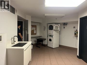 Vancouver apartment for rent - A man is standing in a kitchen with a sink and a dishwasher.