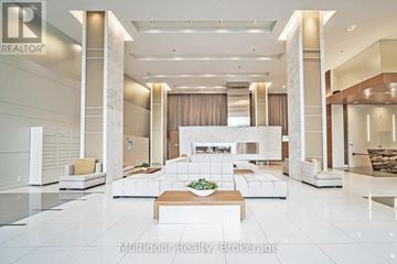 Toronto (Mimico) condo for rent - A spacious, well-lit living room with a central fireplace and a coffee table in the middle.