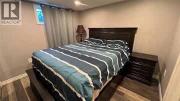 Sarnia apartment for rent - A bed with a blue and white striped comforter in a bedroom.