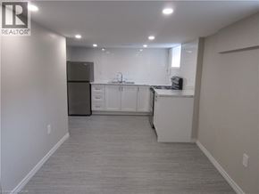 Hamilton apartment for rent - A well-lit, empty kitchen with white cabinets and a black refrigerator.