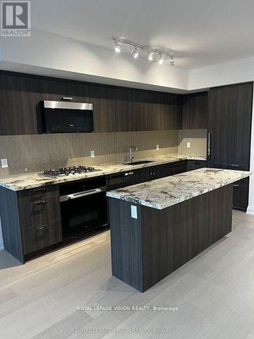 Toronto (Englemount-Lawrence) condo for rent - A modern kitchen with dark wood cabinets and a marble countertop.