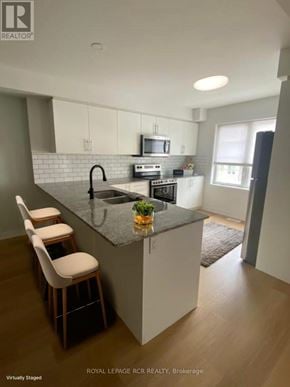Kitchener townhouse for rent - A kitchen with white cabinets and a black countertop.