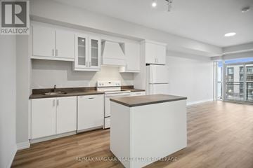 St. Catharines (Oakdale) condo for rent - A kitchen with white cabinets and a wooden island.