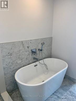 Toronto (Kensington-Chinatown) condo for rent - A white bathtub with a shower head attached to the wall.