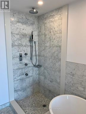 Toronto (Kensington-Chinatown) condo for rent - A white marble bathroom with a shower and a toilet.