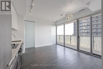 Toronto (Church-Yonge Corridor) condo for rent - A spacious room with a kitchen area and a view of a cityscape through the windows.